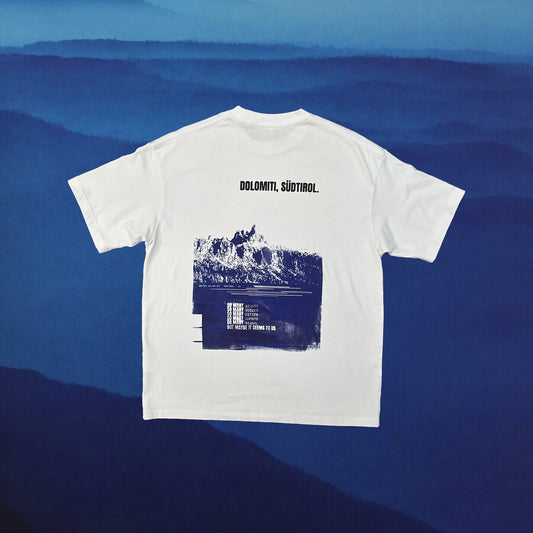 White oversized tee, blue Dolomiti Sudtirol back print, indigo mountain backdrop